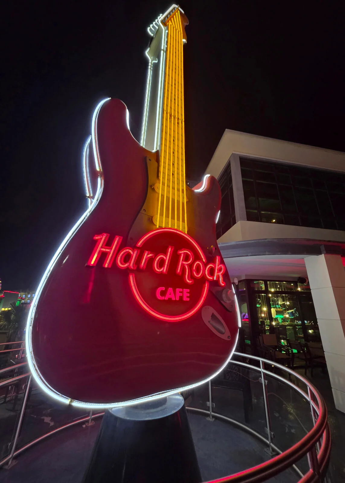 Giant neon guitar sign glowing outside a restaurant at night
