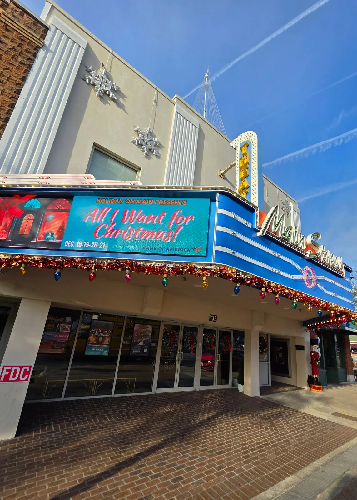 Historic theater storefront with a holiday marquee under a blue sky
