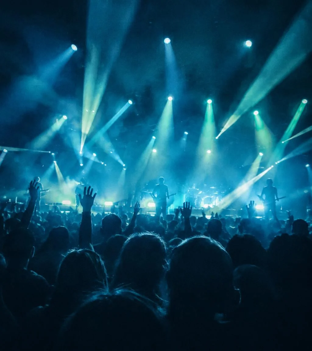 Concert stage lights over a crowd seen from behind